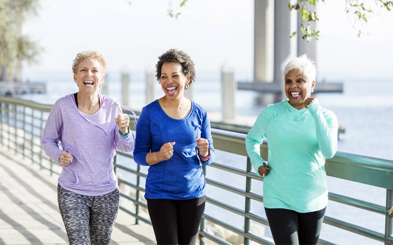 Three women in retirement jogging on a boardwalk